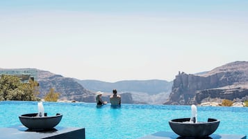 Una piscina al aire libre, sombrillas, sillones reclinables de piscina