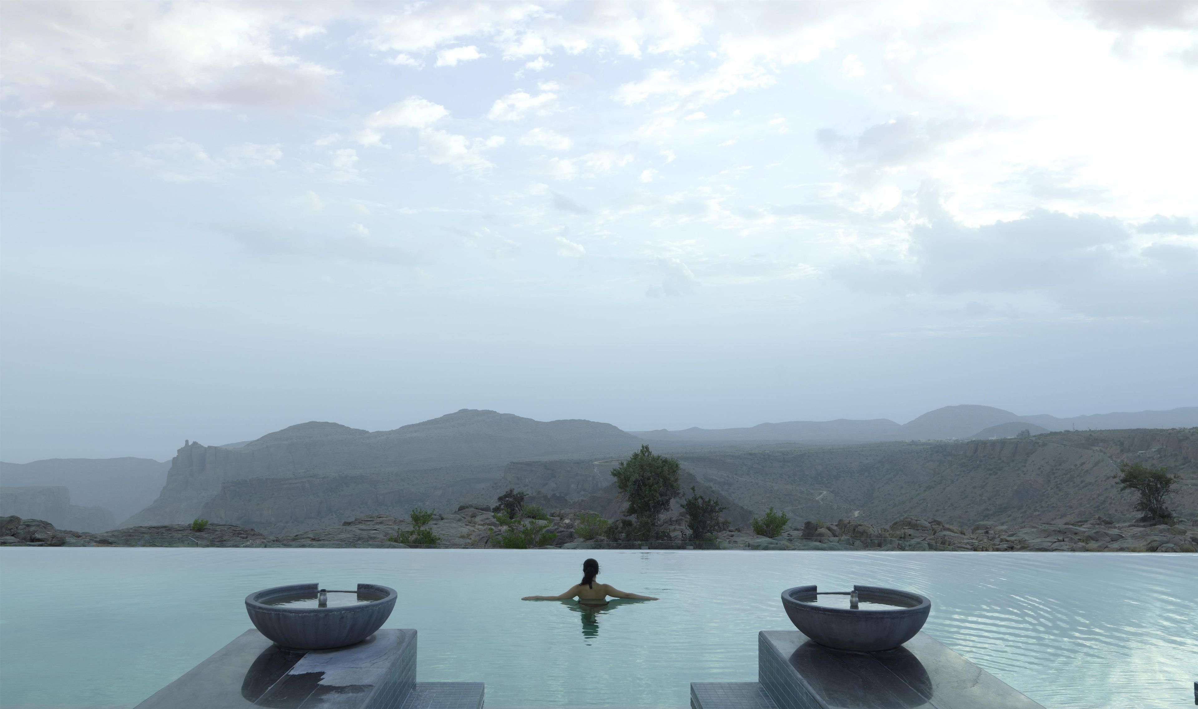 A person relaxing in a pool with a view of mountains.