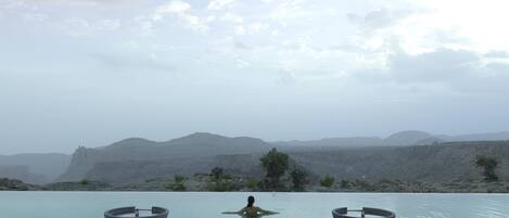 A person relaxing in a pool with a view of mountains.