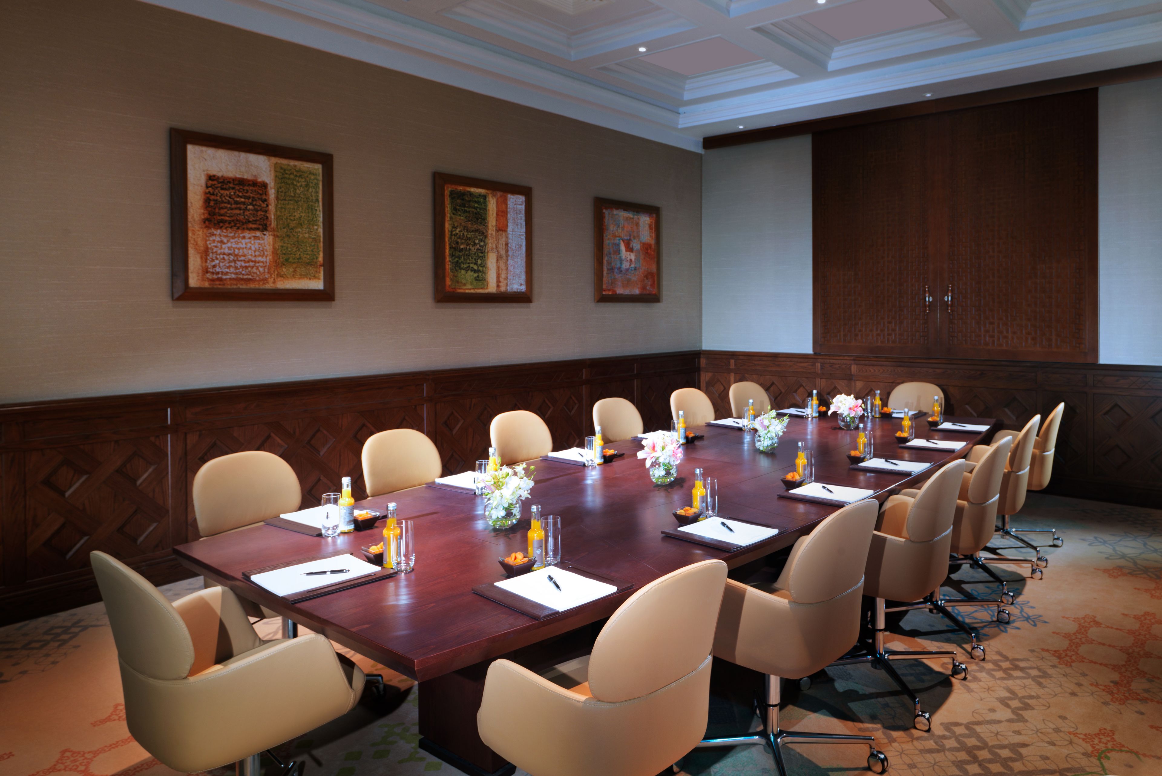 A conference room with a long table, multiple chairs, and framed artwork on the walls.