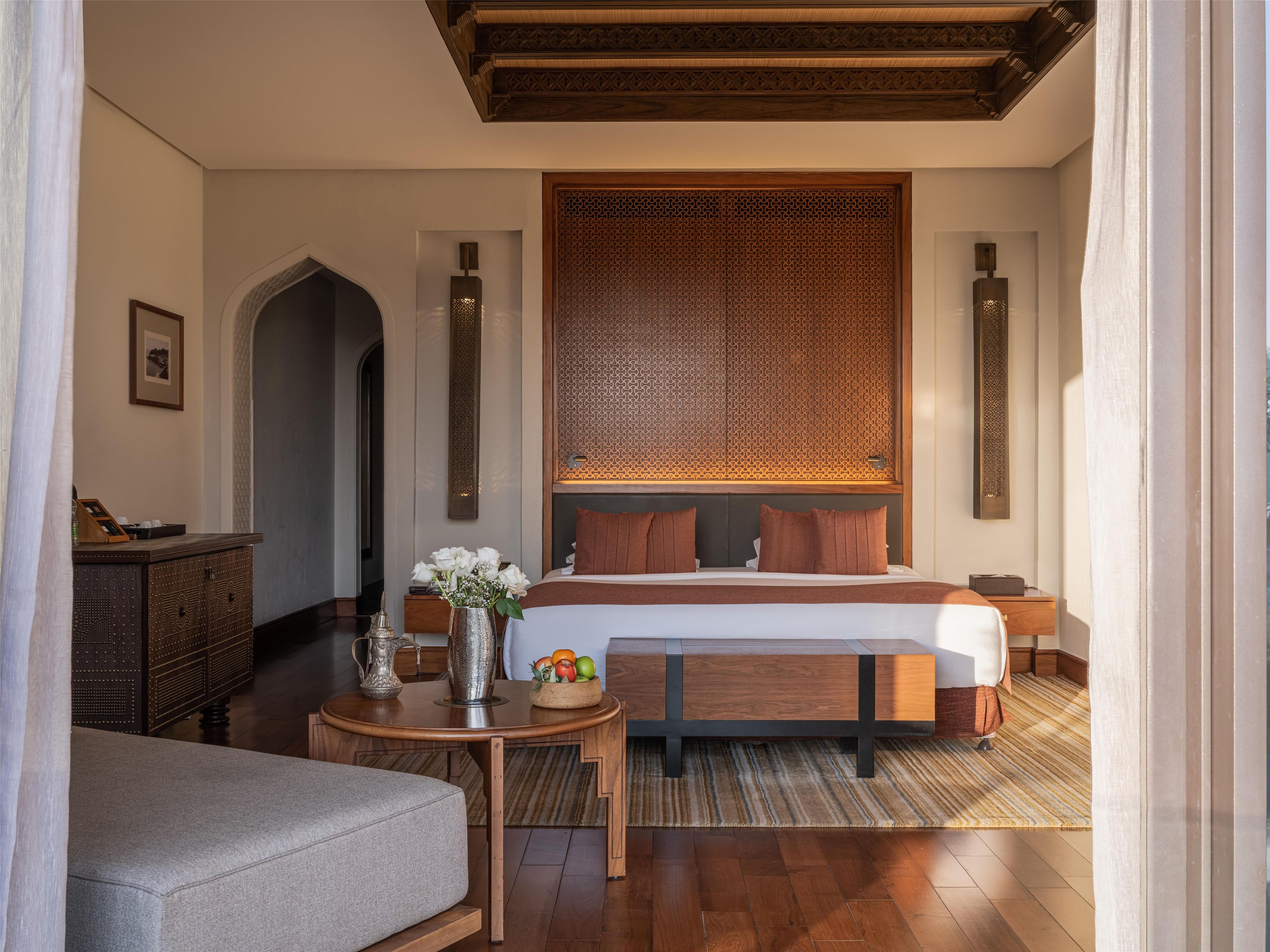 Ein Hotelzimmer mit Bett, Nachttischen, Schreibtisch, Stuhl und einer dekorativen Wandverkleidung.