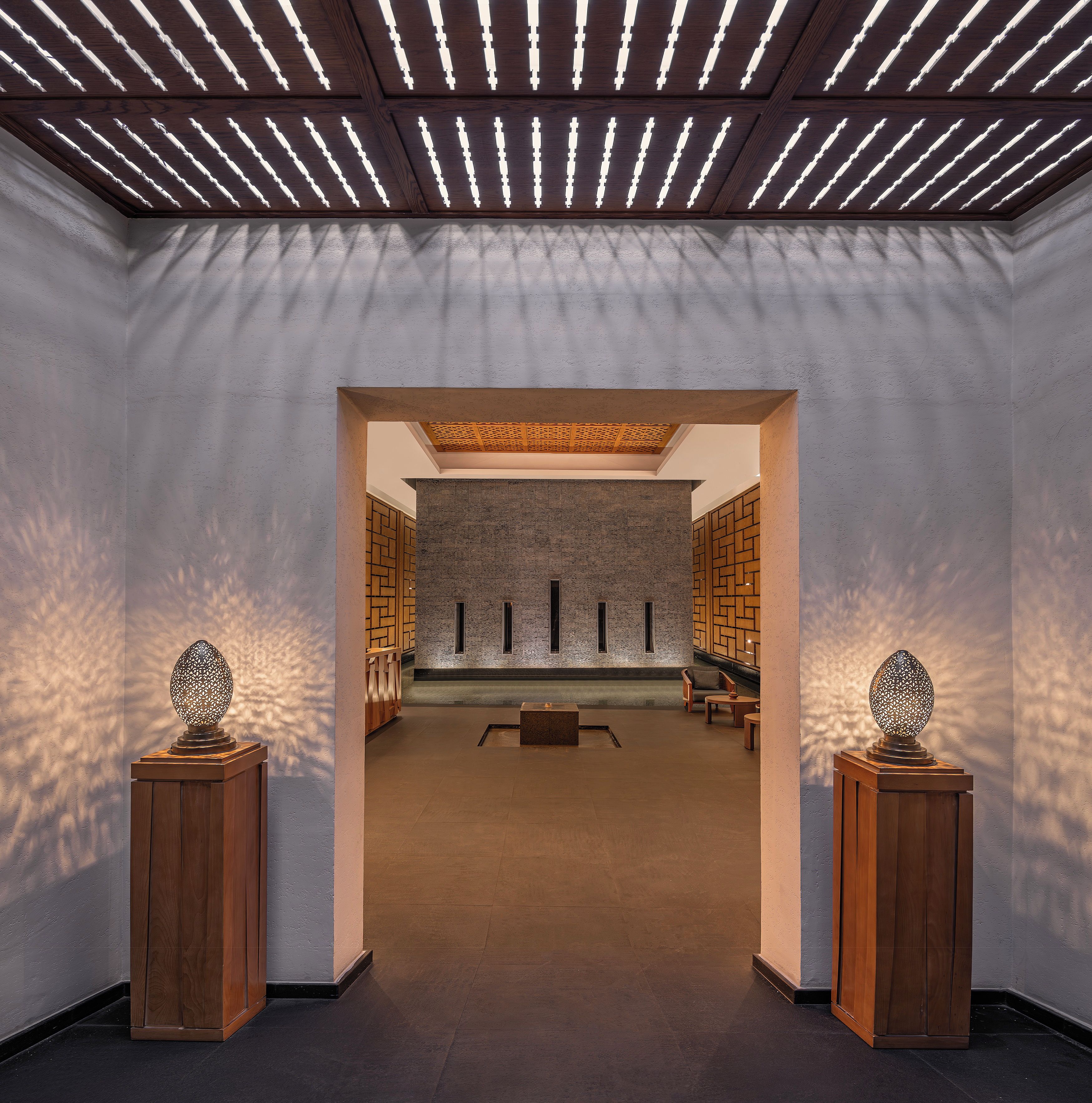 Un interior moderno con techo de madera, pared de ladrillo y una zona de estar con mesas y sillas.