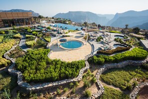 A resort with a central pool, multiple lounge areas, and a mountainous backdrop. - Anantara Al Jabal Al Akhdar Resort (Nizwa)