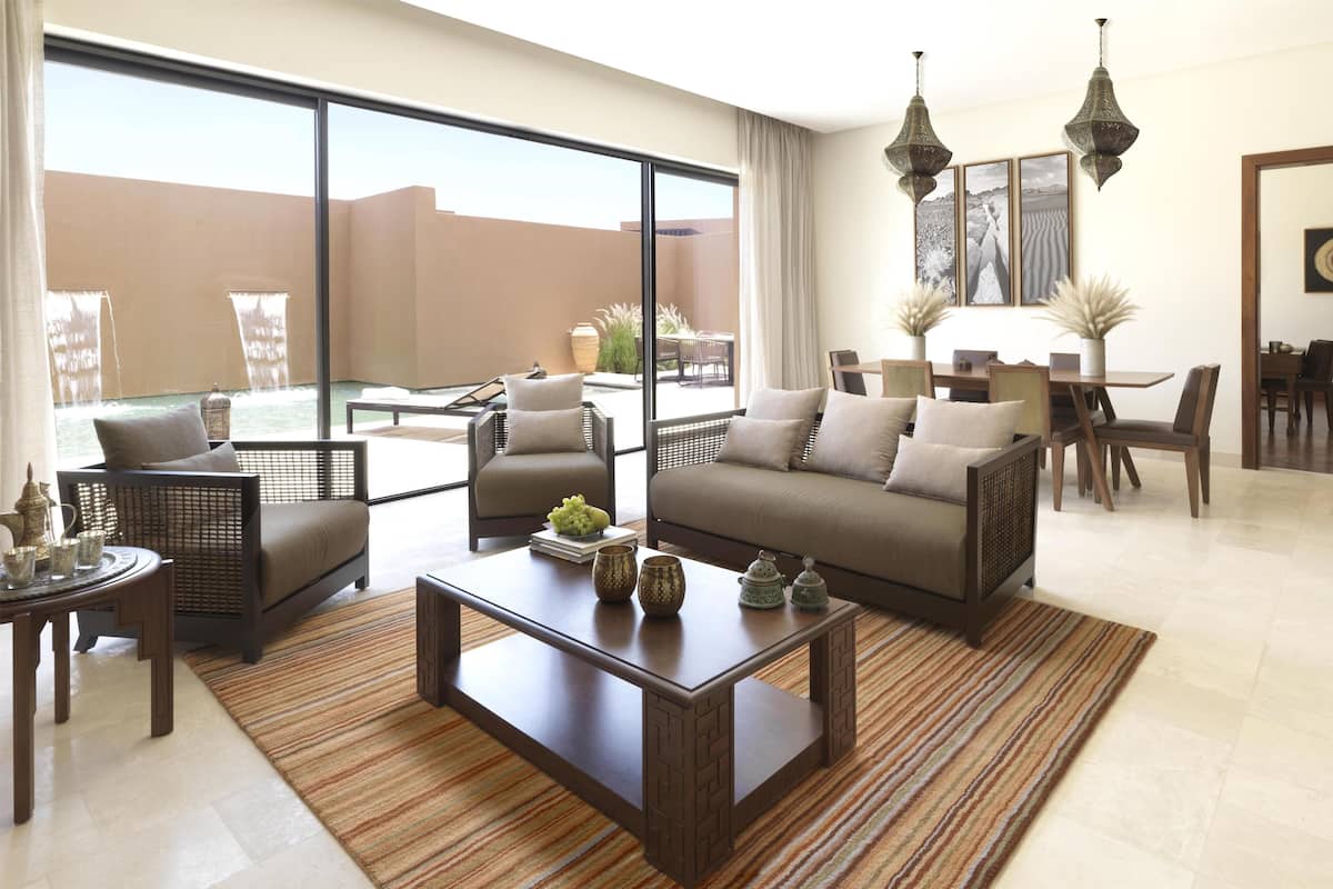 A spacious living area with a large sliding glass door leading to a patio, furnished with a sofa, chairs, and a dining table.