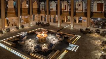 A spacious lobby with a central fire feature, seating arrangements, and a view of the upper floors.