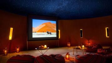 A cozy movie theater with a starry ceiling, a large screen, and comfortable seating.