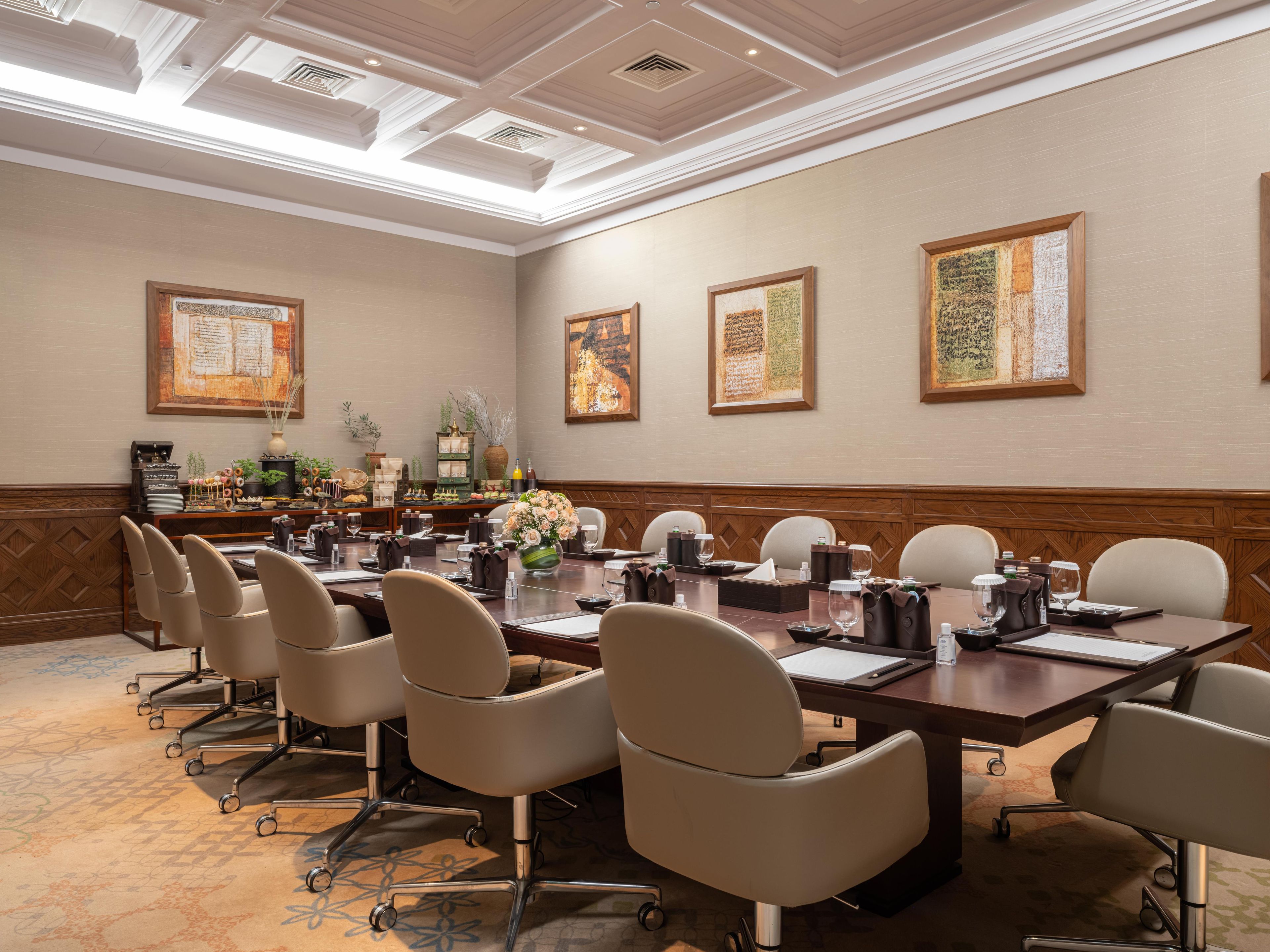 A conference room with a long table, chairs, and framed artwork on the walls.