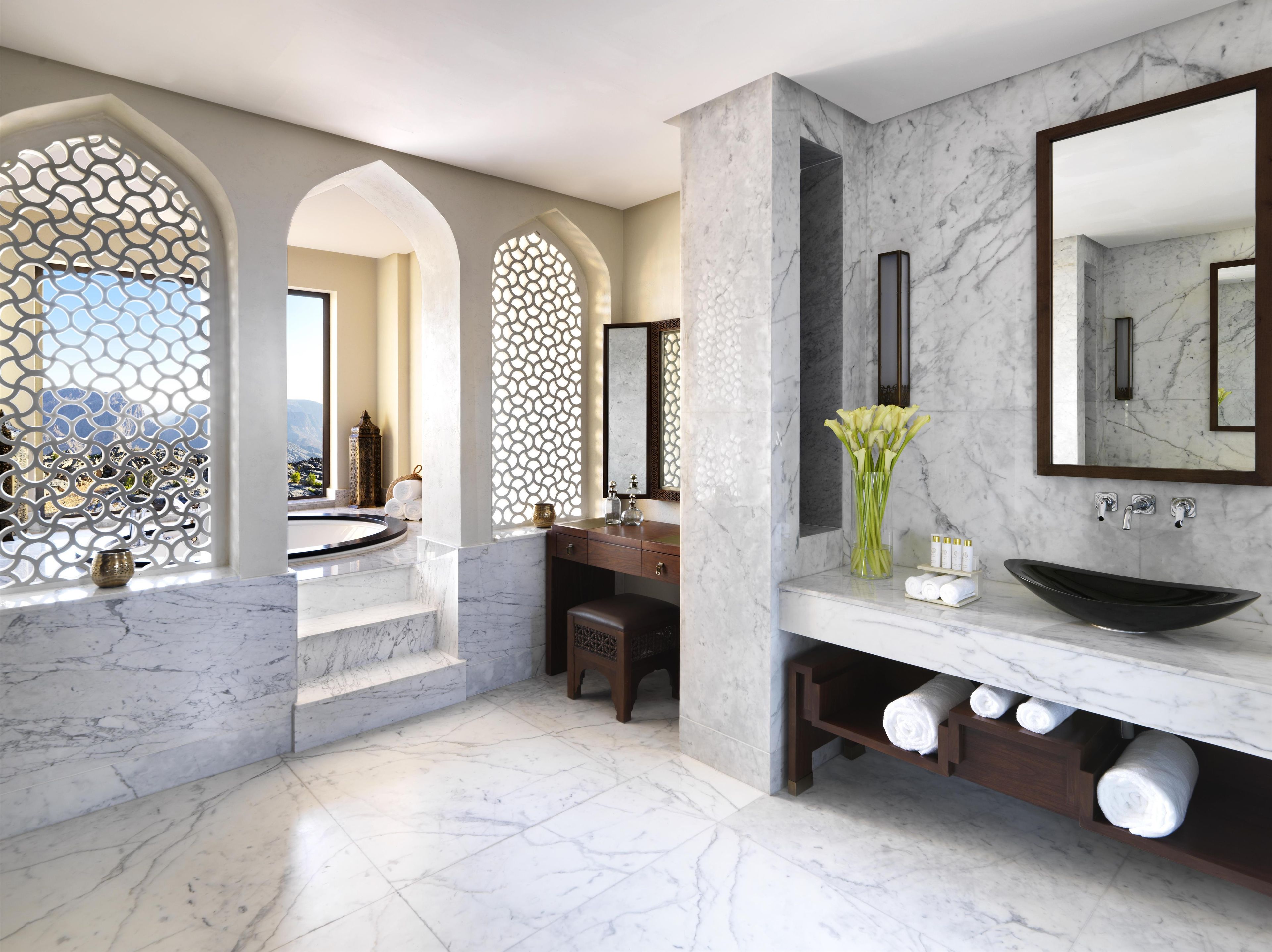 A modern bathroom with a large bathtub, a vanity with a black sink, and a marble floor.