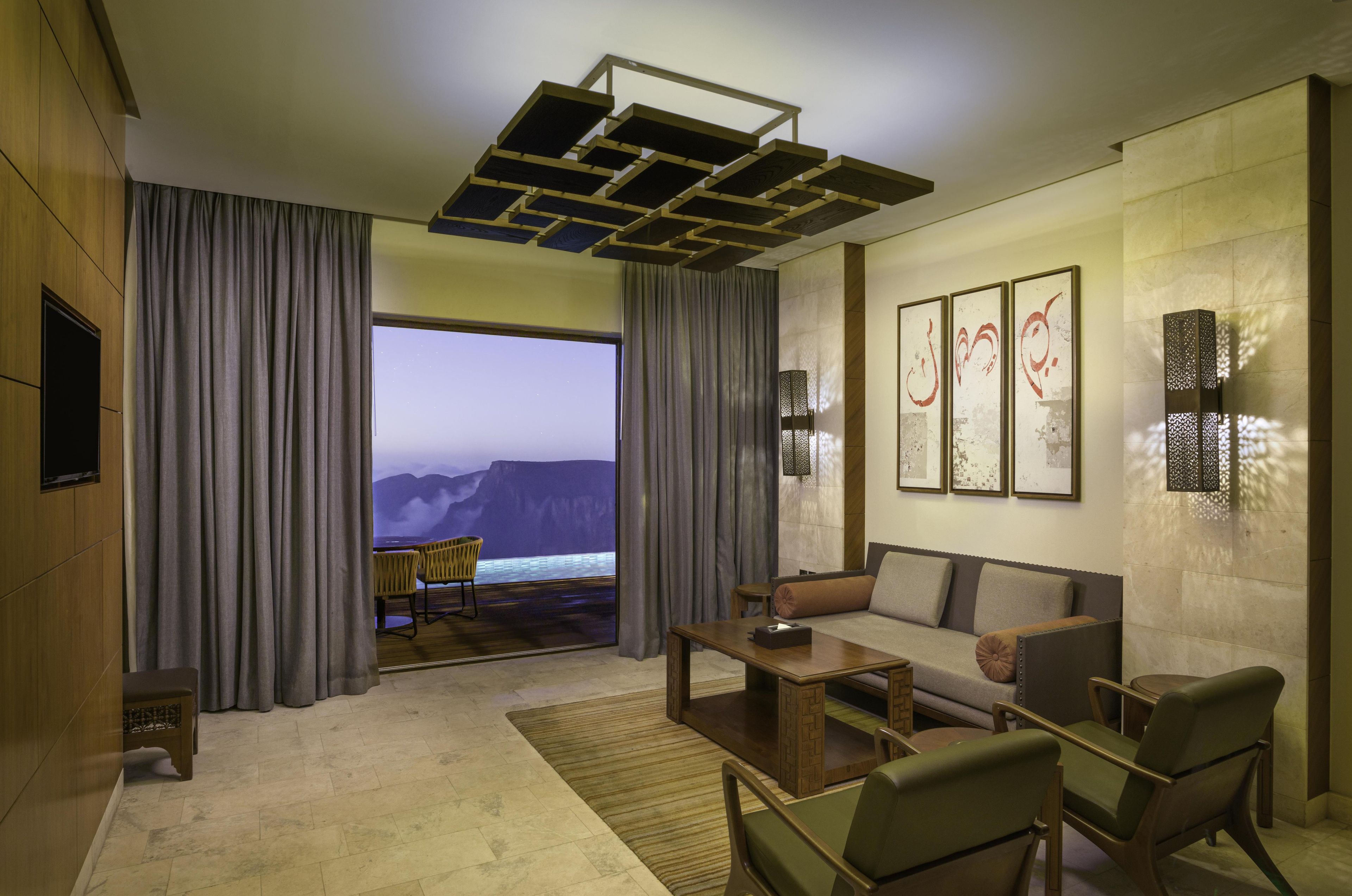 Ein modernes Hotelzimmer mit großem Fenster, einer Couch, einem Couchtisch und einem Fernseher.