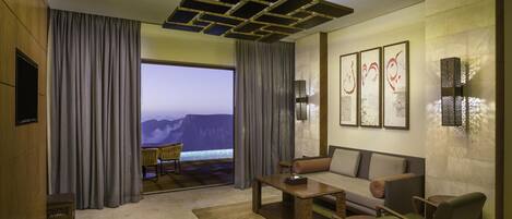 Ein modernes Hotelzimmer mit großem Fenster, einer Couch, einem Couchtisch und einem Fernseher.