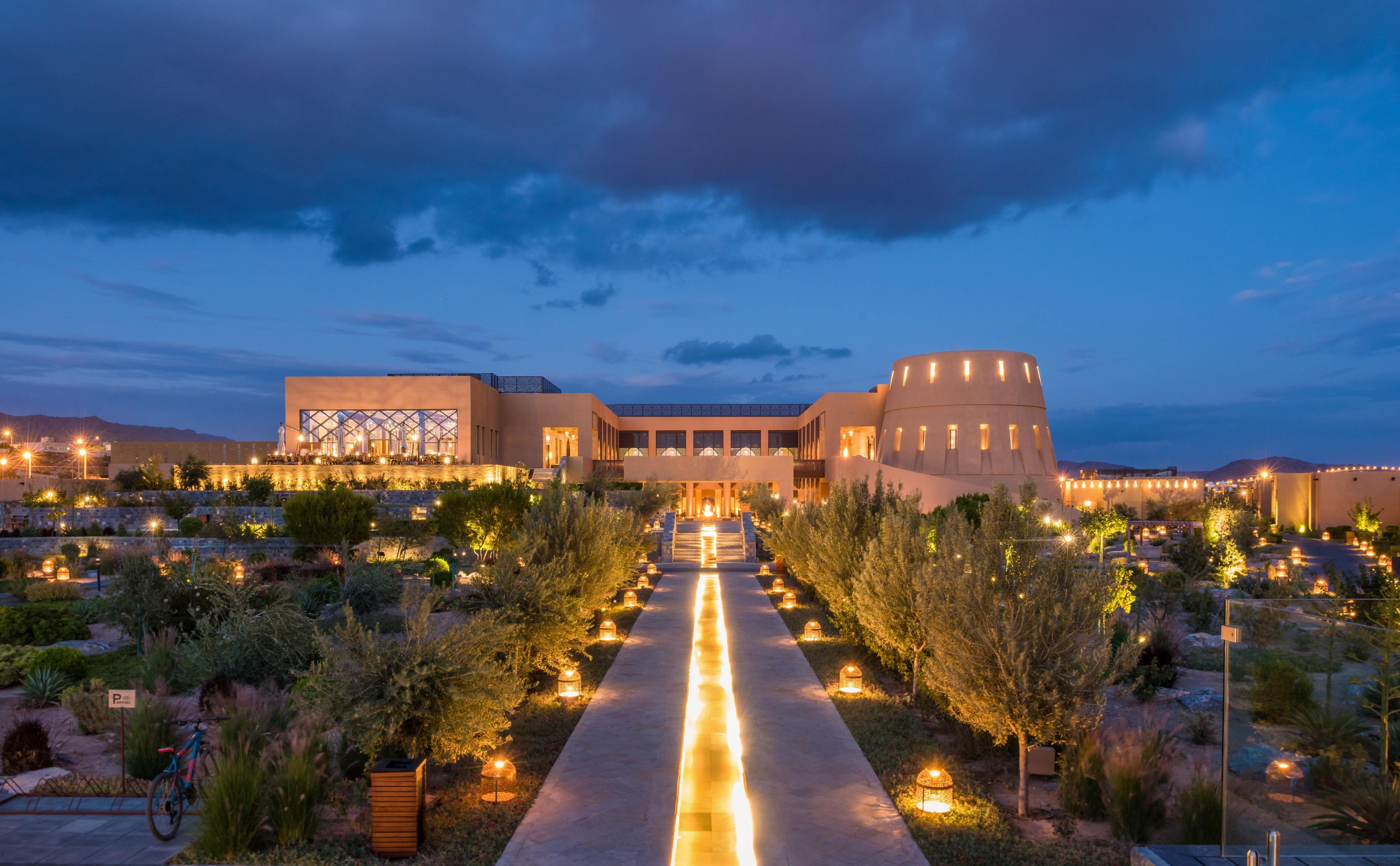 A hotel with a central courtyard, a modern building with a dome, and a pathway leading to the entrance.