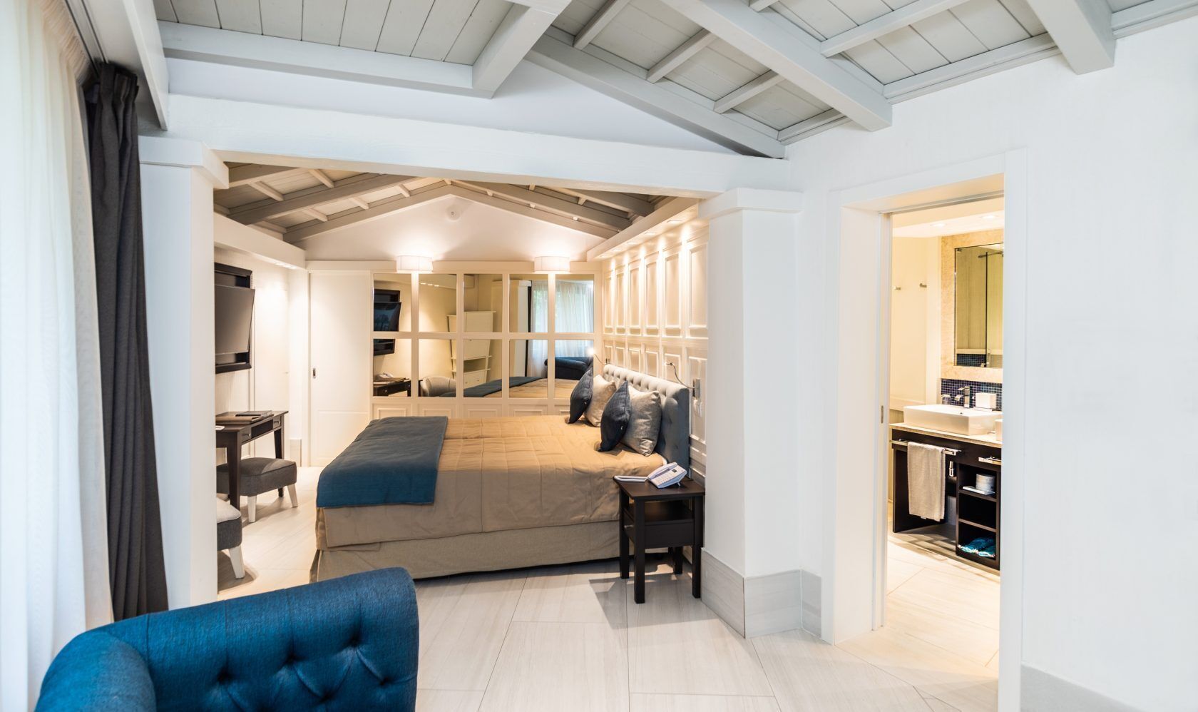 A modern hotel room with a bed, bedside table, and a view into the bathroom.