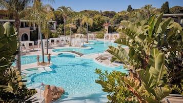 Relax by the serene pool surrounded by lush greenery and palm trees.