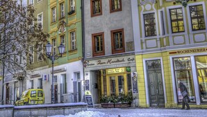 A row of colorful buildings with a café and a tram. - Zum Handtuch (Bautzen)