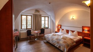 A hotel room with a large bed, two chairs, a small table, and a window with curtains. - Zum Handtuch (Bautzen)