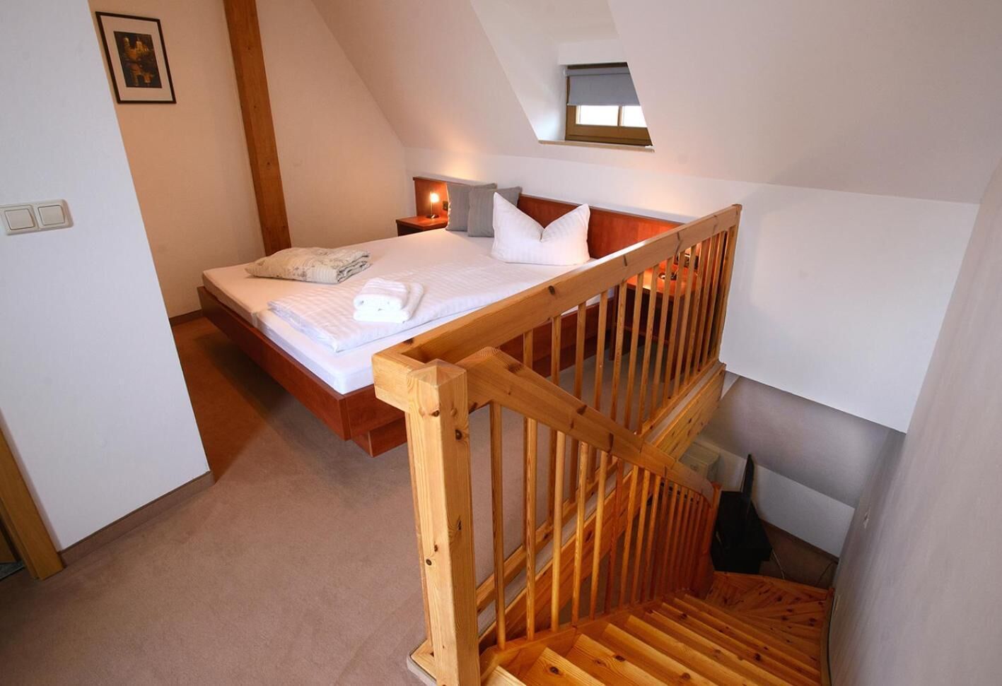 Une chambre à coucher avec un lit en bois, une table de chevet et une petite fenêtre donnant sur le ciel.