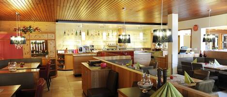 A restaurant with wooden ceiling, bar area, and seating arrangements.