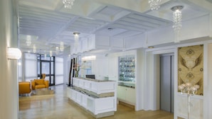 A spacious lobby with a modern design, featuring a reception desk, seating area, and decorative lighting. - Hotel Hellers Twenty Four 2 (Friedrichshafen)