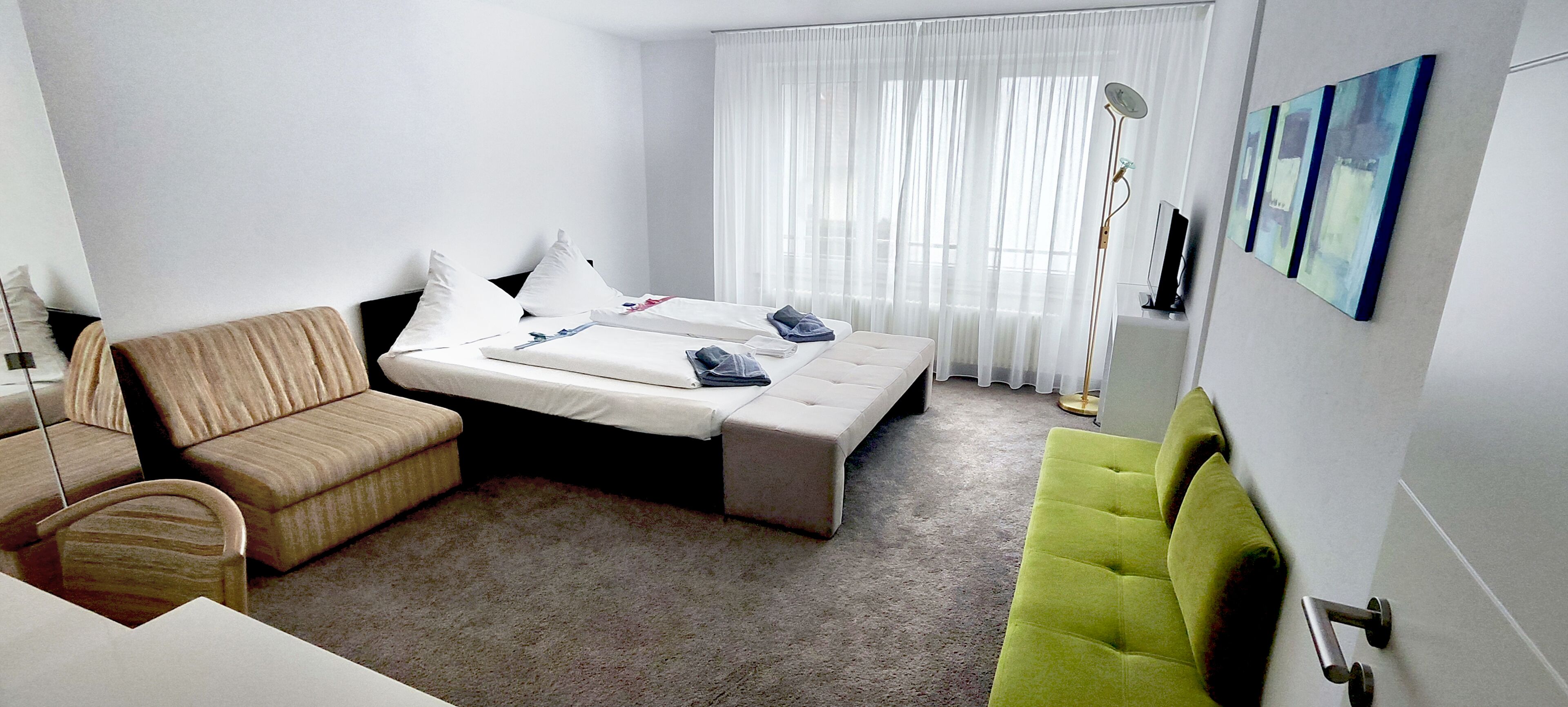 A hotel room with a bed, a sofa, a chair, and a desk.