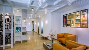 A modern hotel lobby with a reception desk, seating area, and a display of various items. - Hotel Hellers Twenty Four 2 (Friedrichshafen)