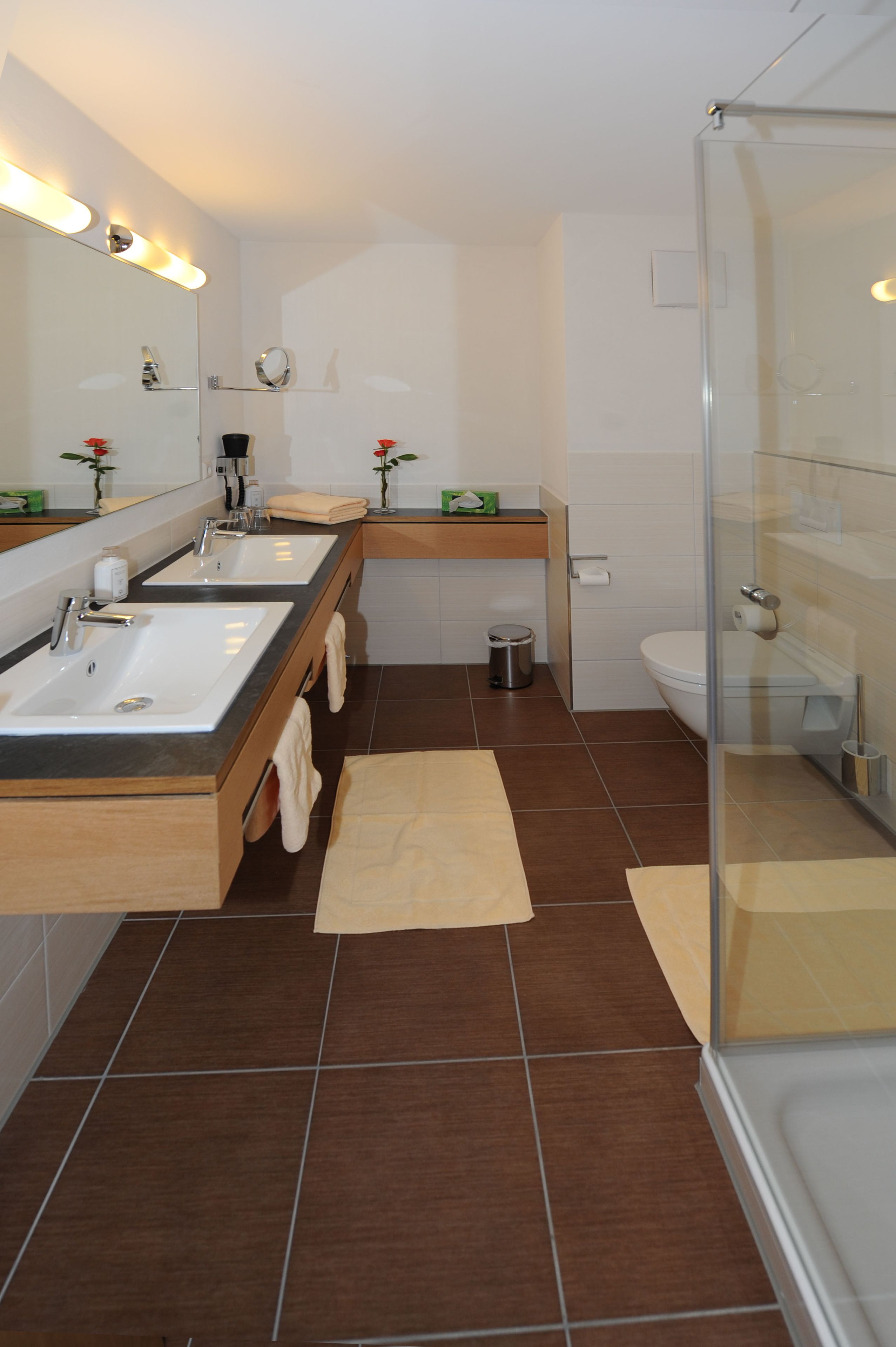Une salle de bain moderne avec deux lavabos, une douche à parois de verre et des toilettes.
