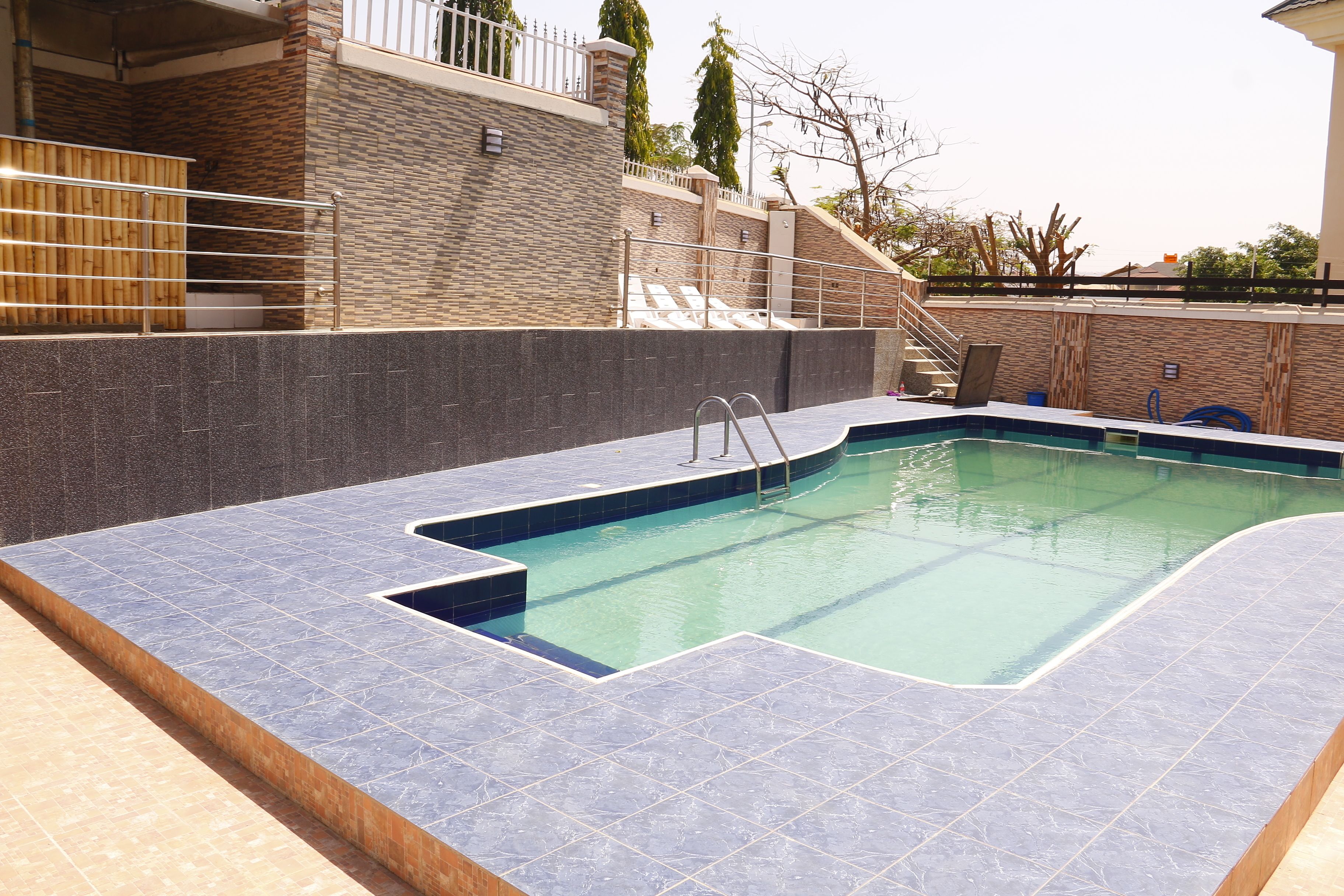 Una piscina al aire libre, sombrillas, sillones reclinables de piscina