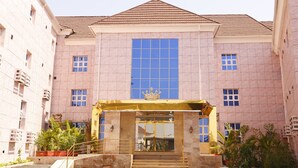 A building with a large central window, a golden entrance canopy, and a tiled roof. - Barca-Liga Hotels (Abuja)