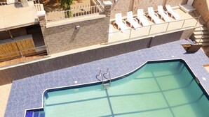 A rooftop swimming pool with a blue tiled deck, a ladder, and lounge chairs. - Barca-Liga Hotels (Abuja)