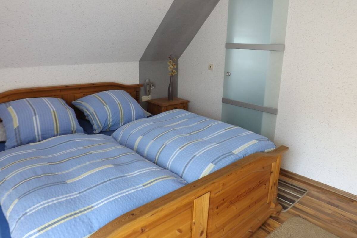 A bedroom with a wooden bed, a nightstand, and a frosted glass door.