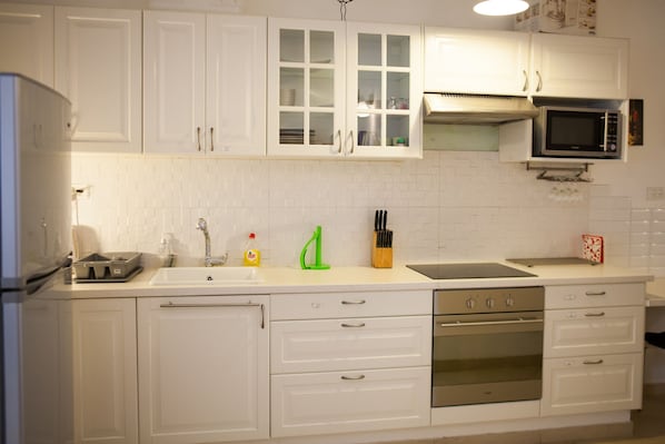 A kitchen with white cabinets, a stainless steel oven, a microwave, and a sink.