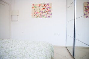 A bedroom with a bed, a wall-mounted light, and a door with a mirror.