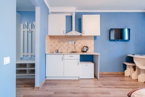 A compact kitchen with white cabinets, a small refrigerator, and a coffee maker on the counter. - Potemkin's Favorite Suites (Odesa)