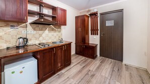 A kitchen with wooden cabinets, a stainless steel sink, a coffee maker, and a white mini-fridge. - Potemkin's Favorite Suites (Odesa)