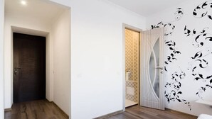 A room with a wooden floor, a dark door, and a white wall with black floral wallpaper. - Potemkin's Favorite Suites (Odesa)