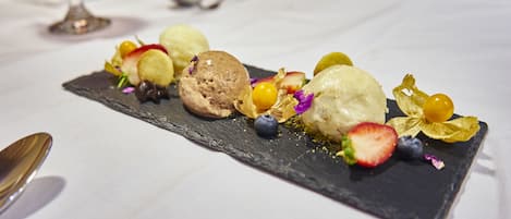 A dessert plate with various fruits and ice cream on a slate serving board.