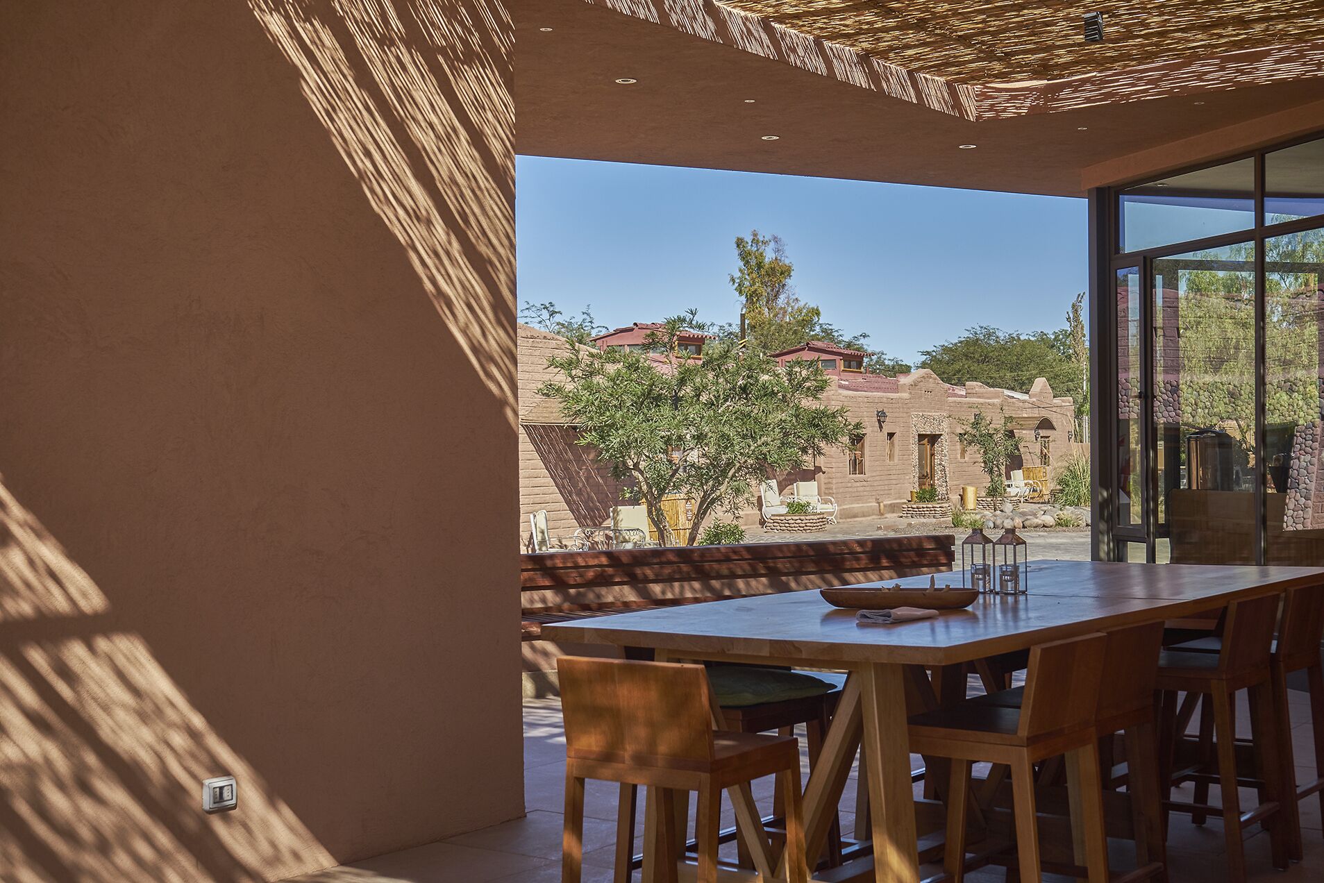 An outdoor dining area with a table and chairs, a wicker umbrella, and a view of traditional buildings in the background.