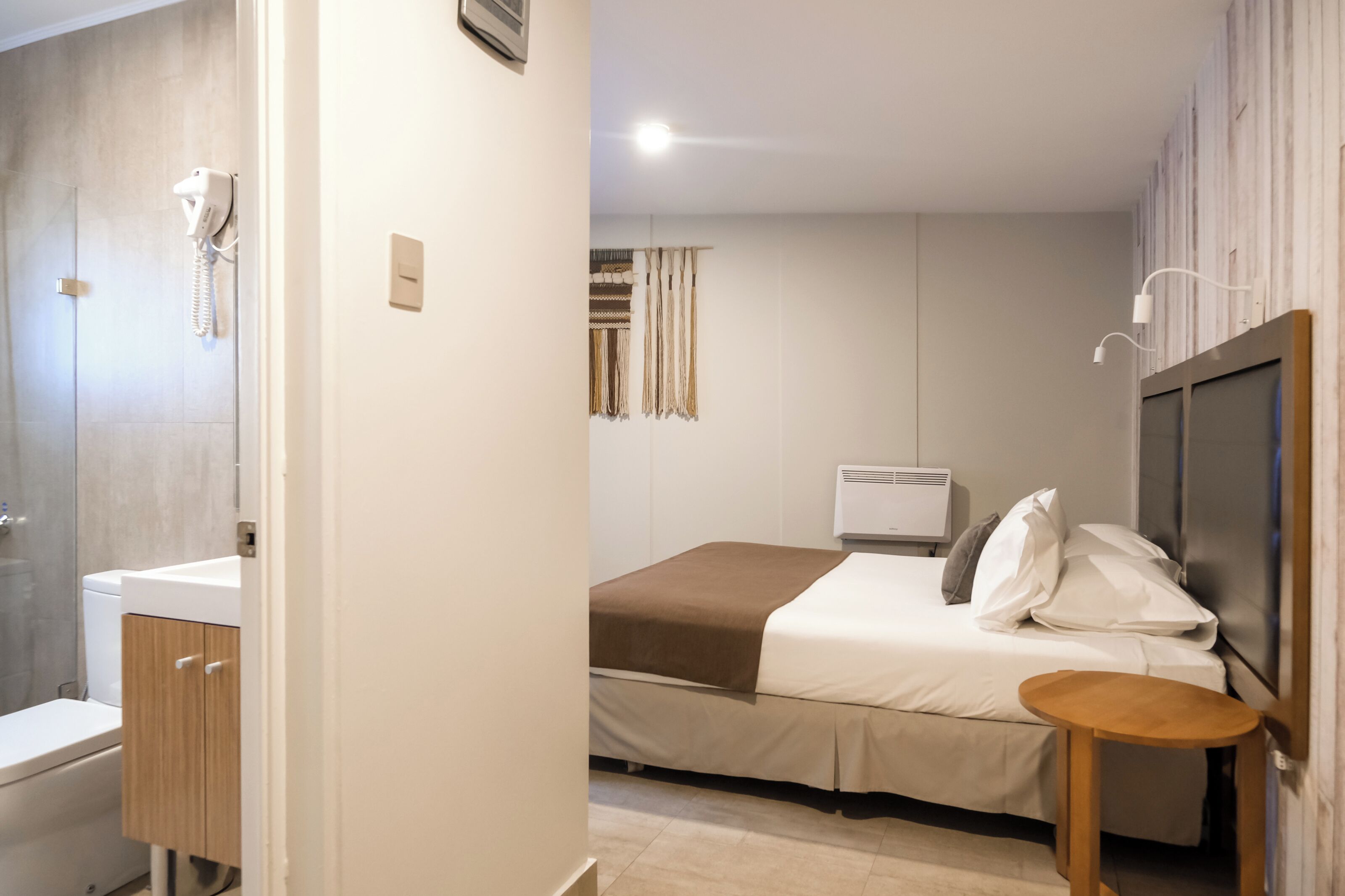 Una habitación de hotel con cama, mesita de noche y zona de ducha.