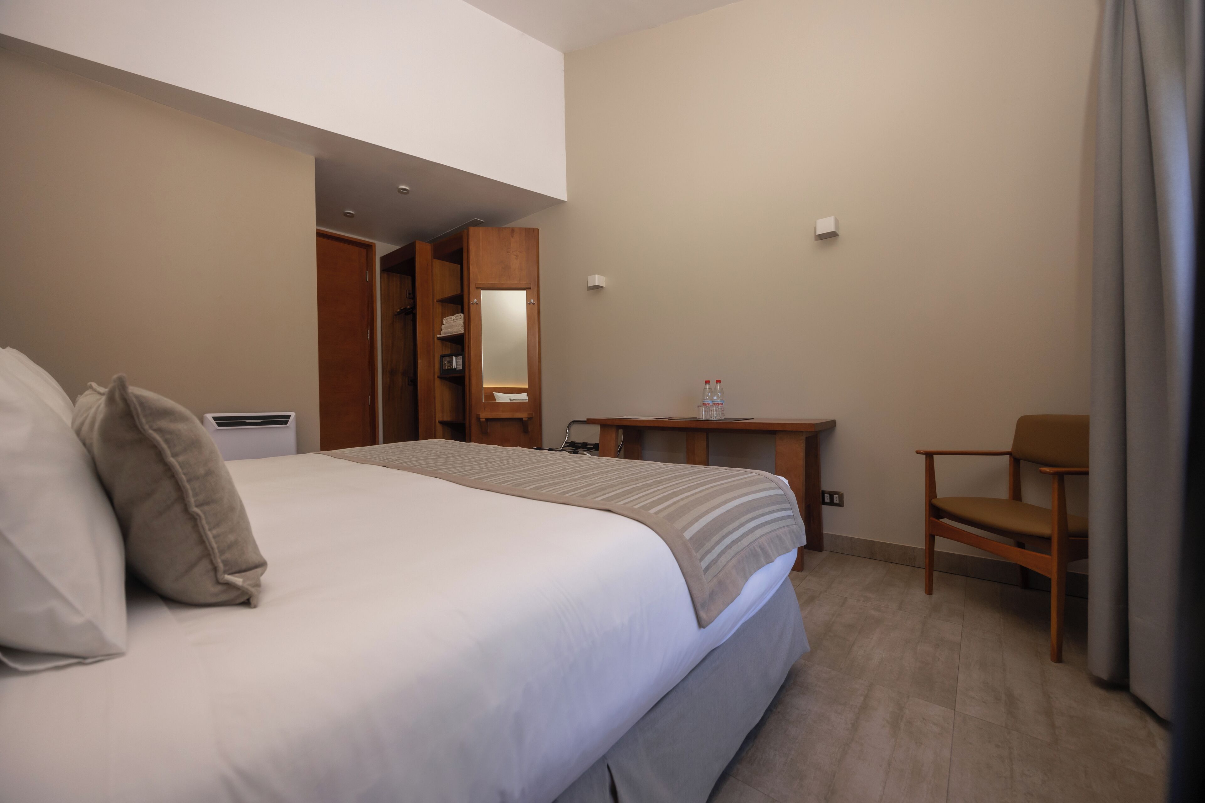 Ein Hotelzimmer mit einem großen Bett, einem Holztisch, einem Stuhl und einem Kleiderschrank.