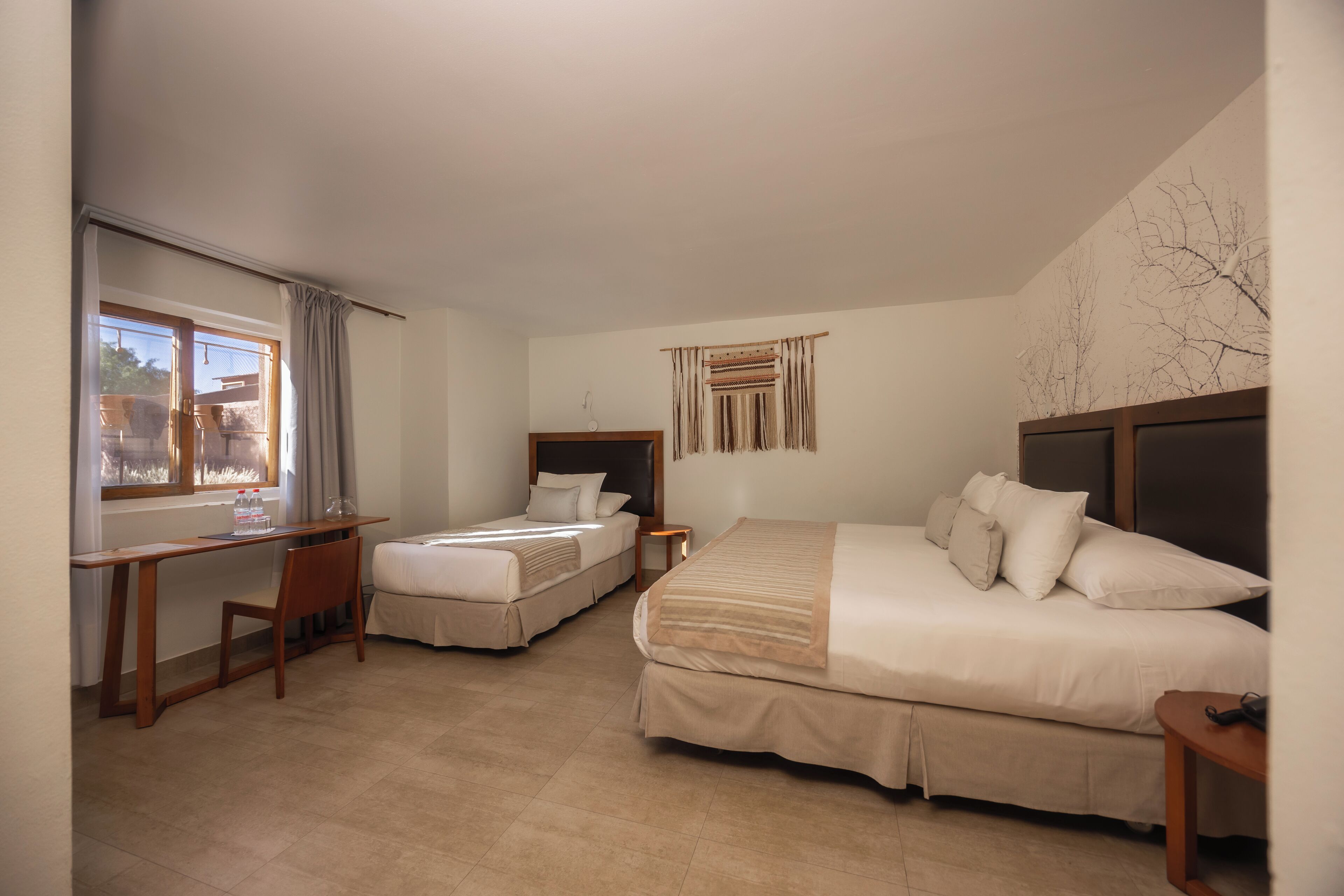 Une chambre d’hôtel avec deux lits, un bureau et une chaise.