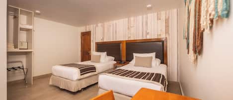 Une chambre d’hôtel avec deux lits, une table en bois et une armoire.
