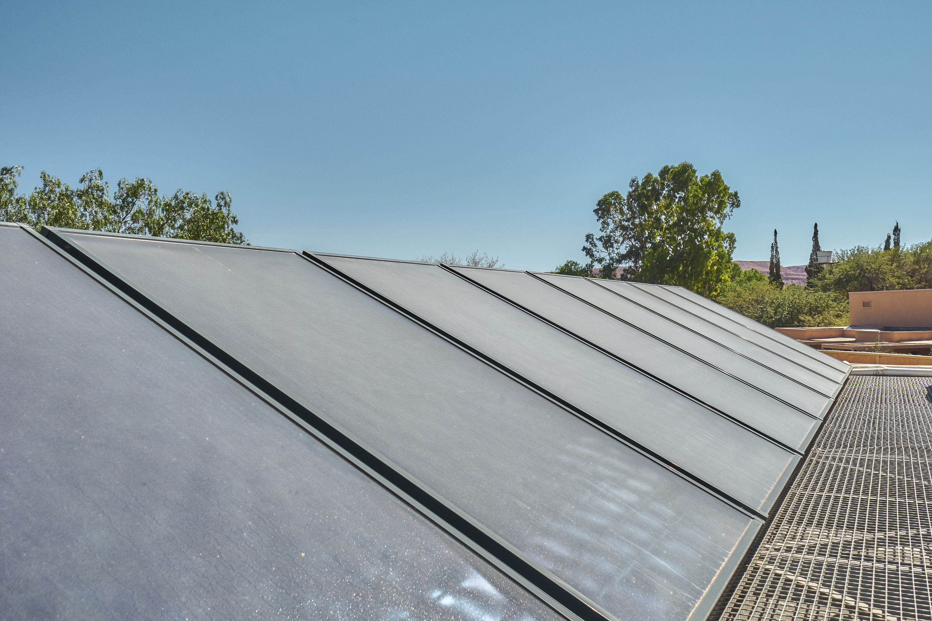 A series of large, flat, dark-colored solar panels on a rooftop.