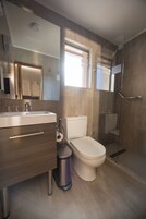 Un baño moderno con lavamanos, inodoro y cabina de ducha de vidrio.