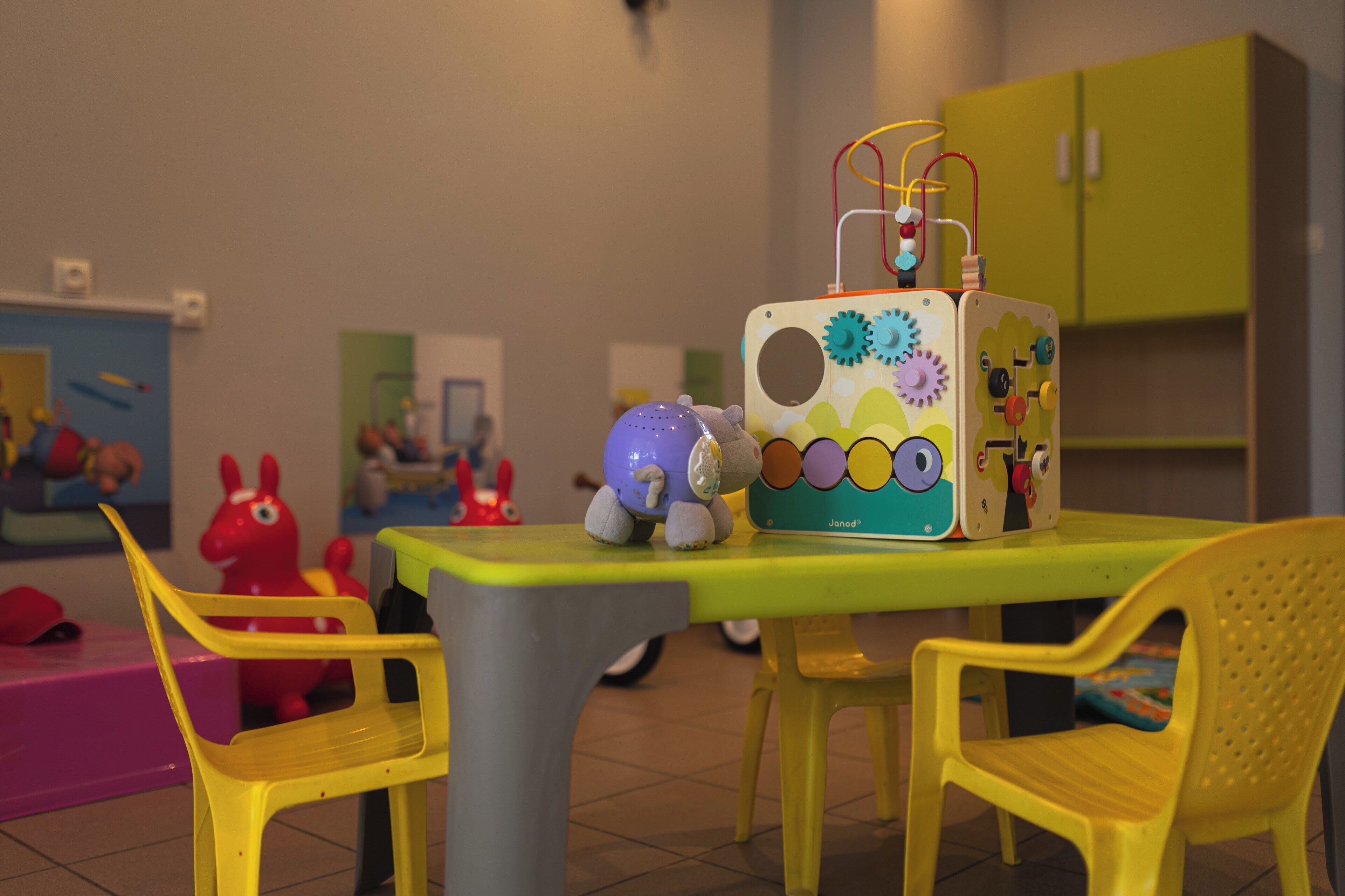 A children's play area with a table and chairs, a toy robot, and a colorful cabinet.