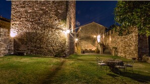 A courtyard with stone walls, a grassy area, and outdoor seating. - Castello di Mugnana (Greve in Chianti)