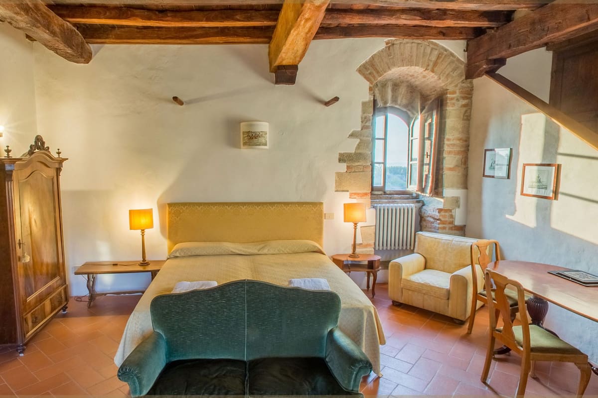 Un dormitorio con una cama grande, muebles de madera, una chimenea de piedra y vistas al exterior.