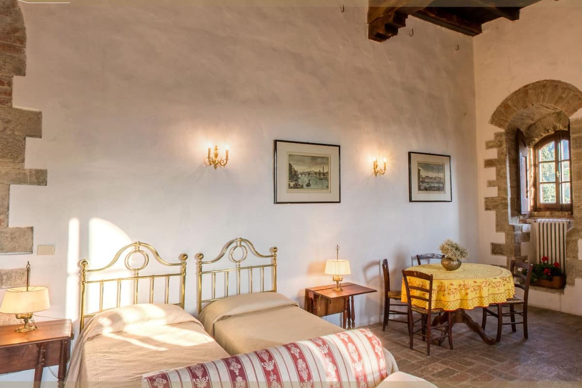 Un dormitorio con dos camas, una mesa de comedor y una pequeña cocina.