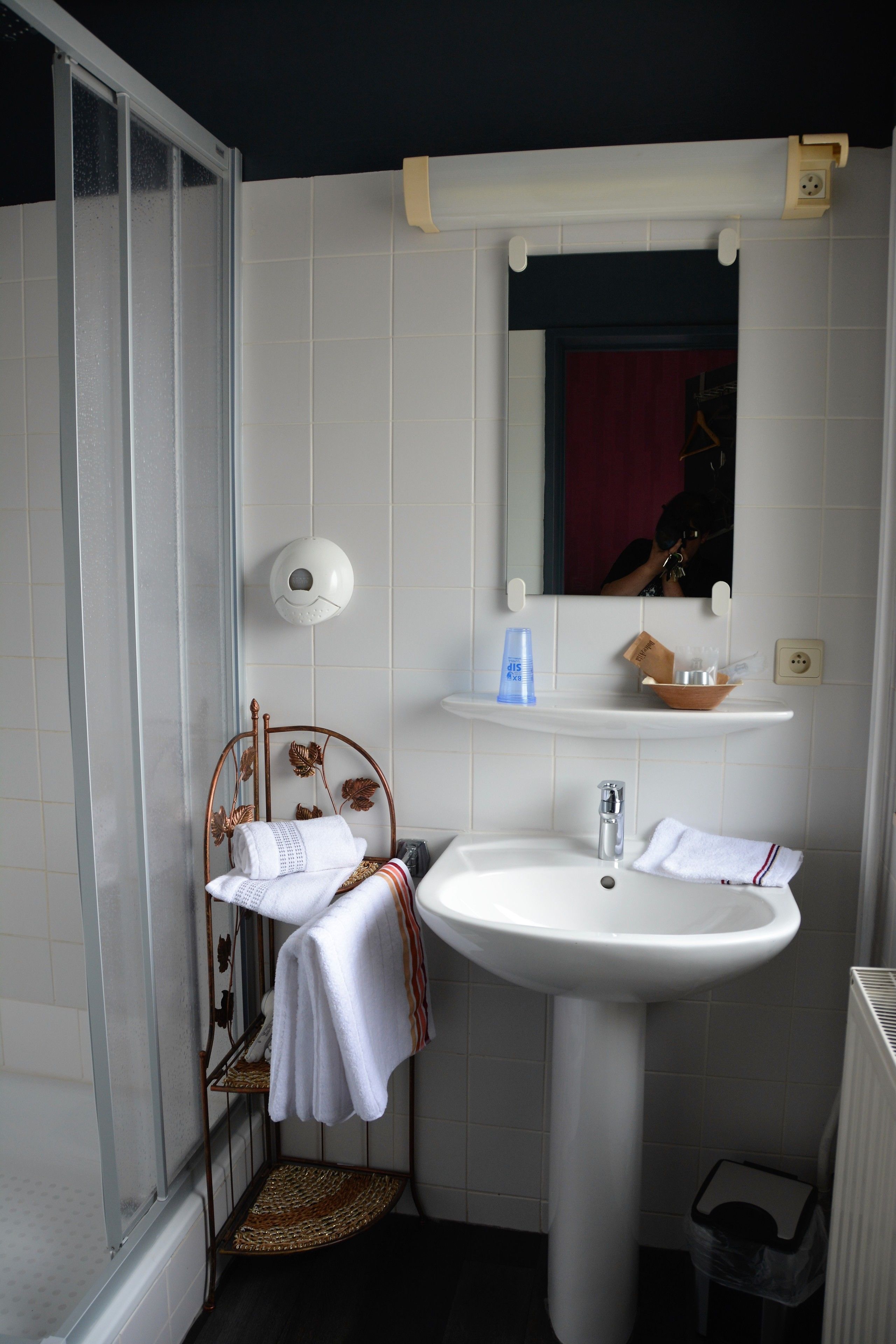 A bathroom with a white sink, a mirror, and a shower area.