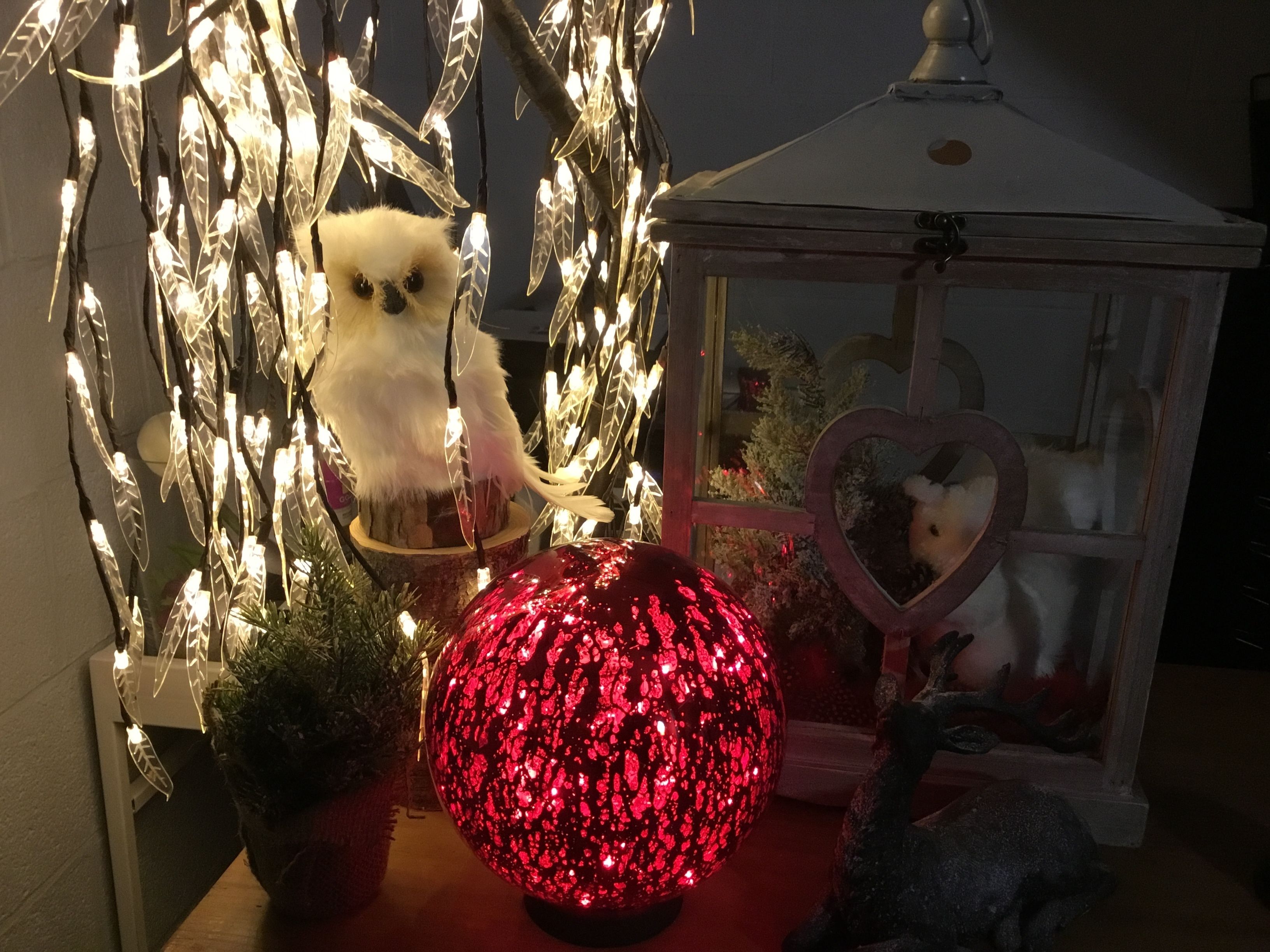 Una exhibición decorativa con un peluche, un adorno con forma de corazón y un objeto esférico rojo.
