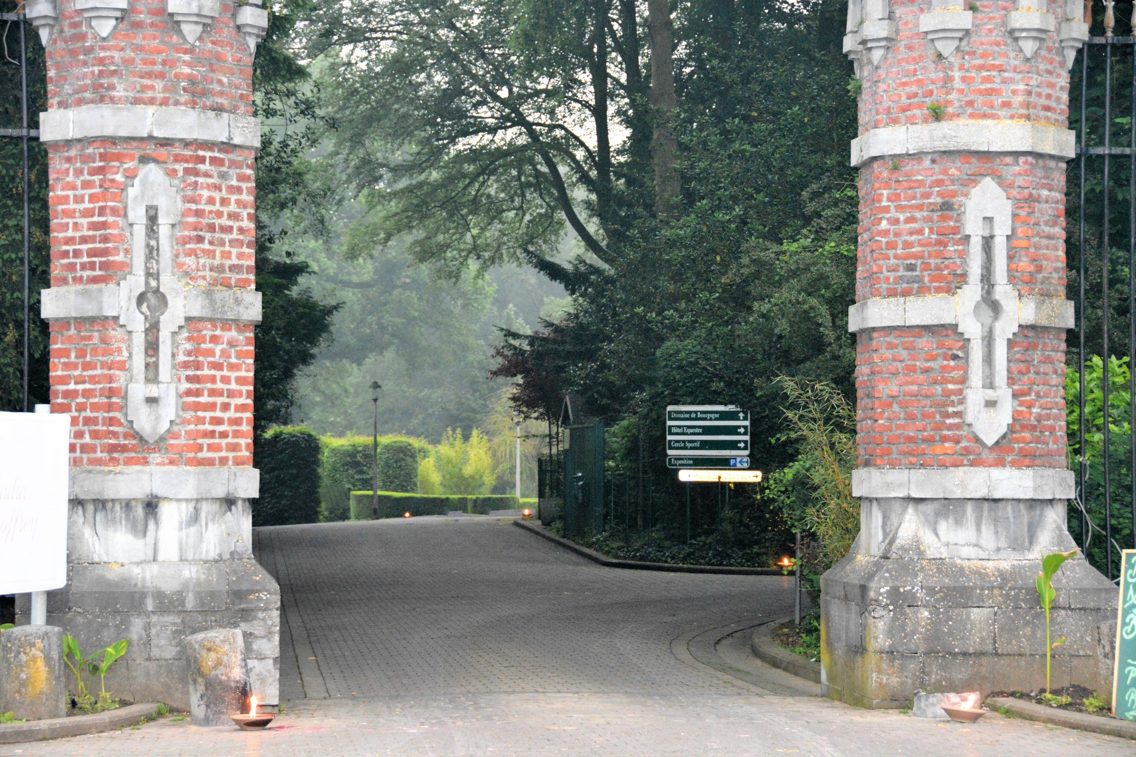 A brick gate with a sign indicating directions to various locations.
