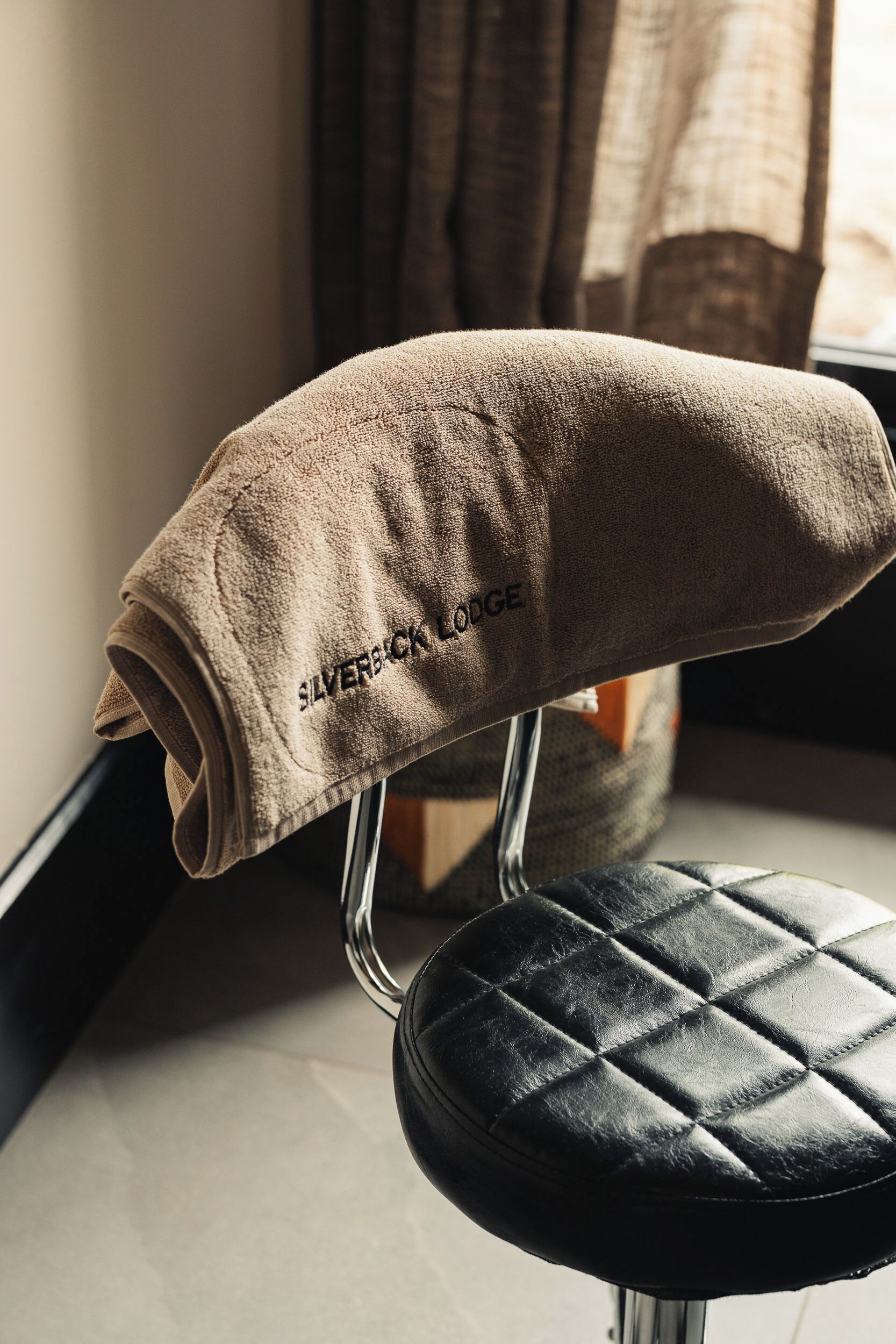 A chair with a folded beige towel on it, and the text "SILVERBACK LODGE" is visible.